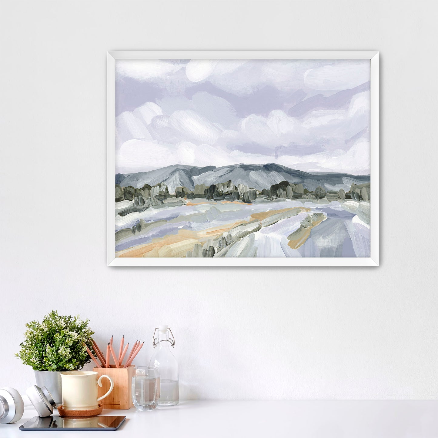 Framed watercolor landscape painting depicting mountains and fields under a cloudy sky.