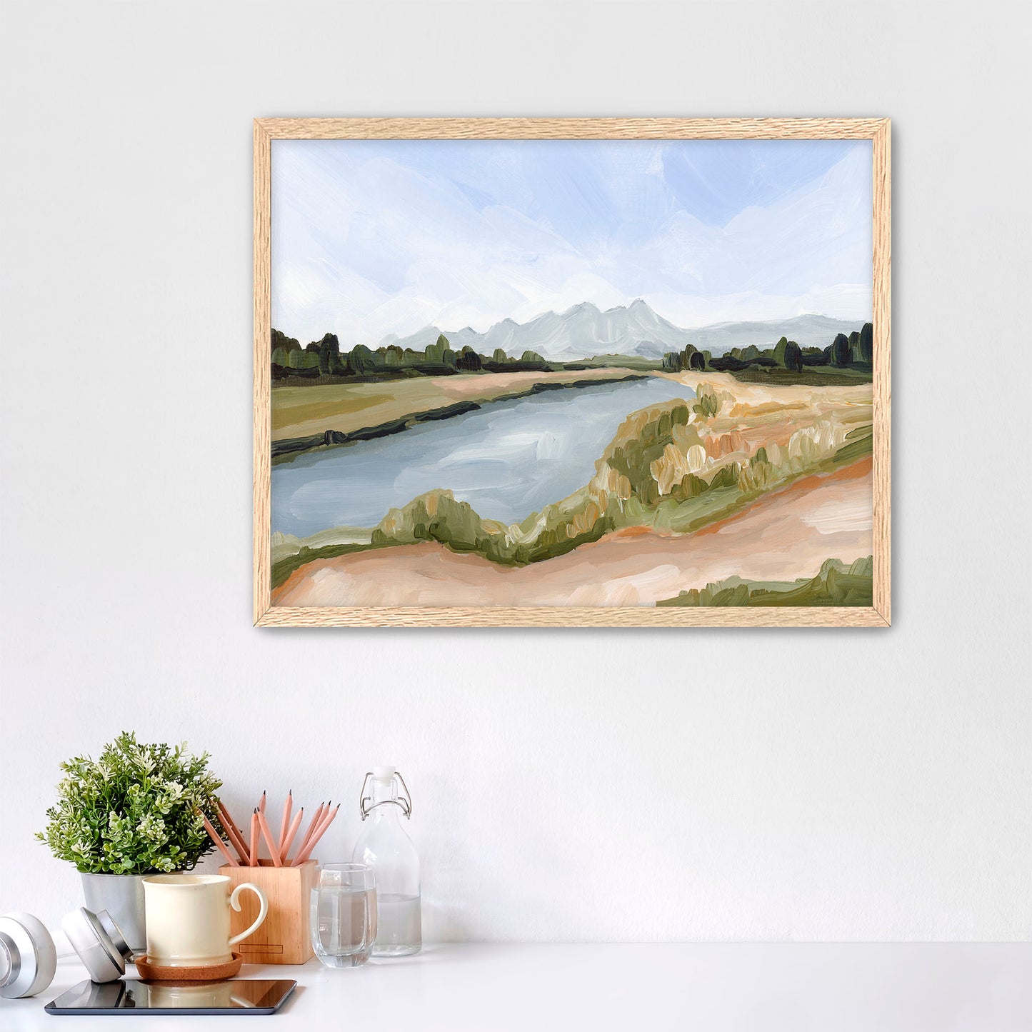 Framed landscape painting depicting a river winding through countryside with distant mountains.