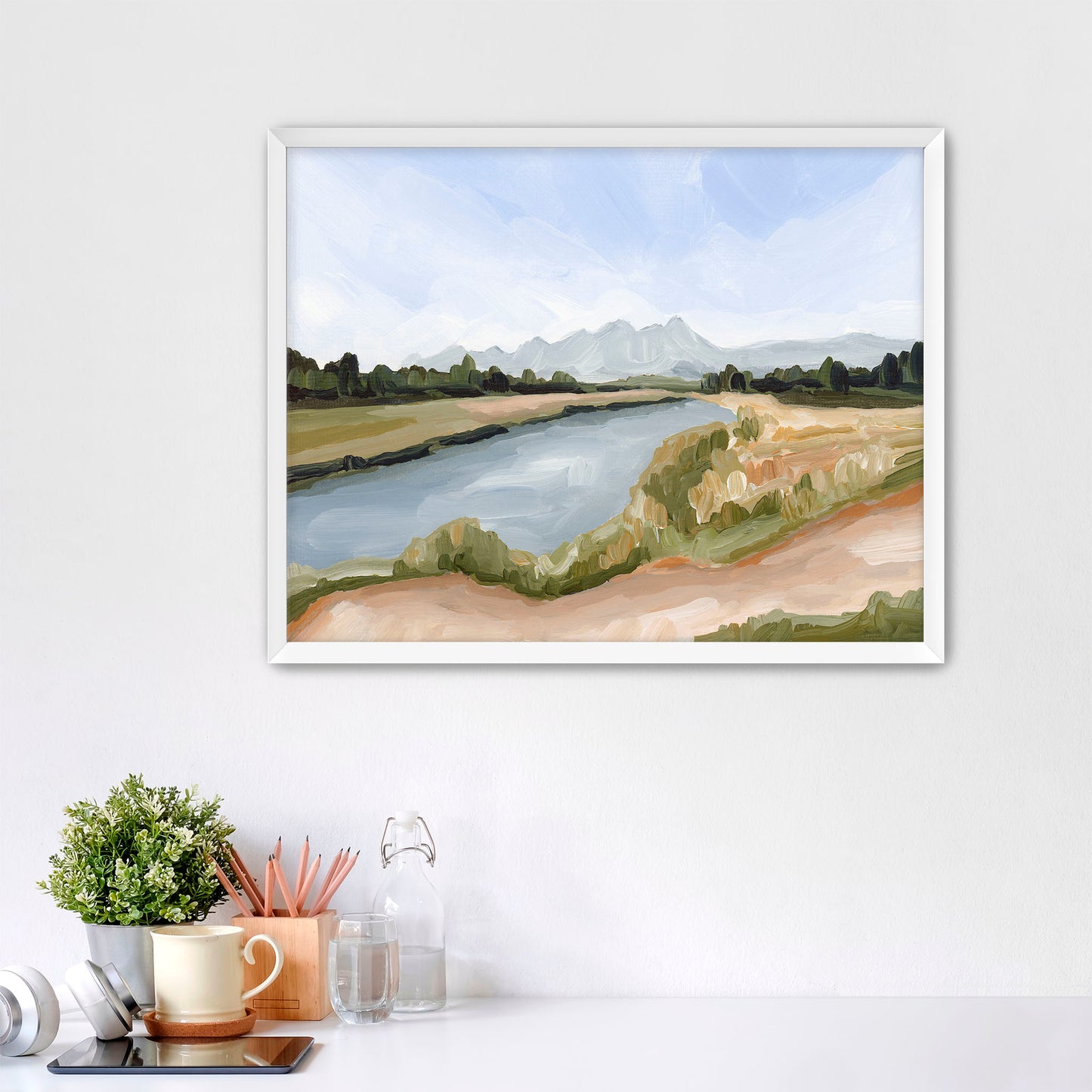 Framed watercolor painting of a serene river landscape with distant mountains.