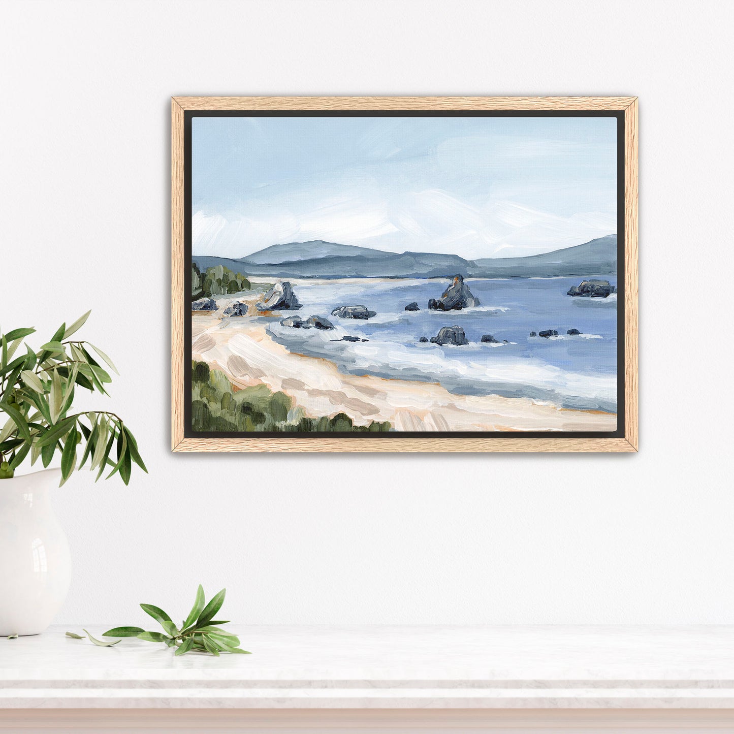 Framed painting of a serene coastal landscape with a beach, water, and distant mountains.