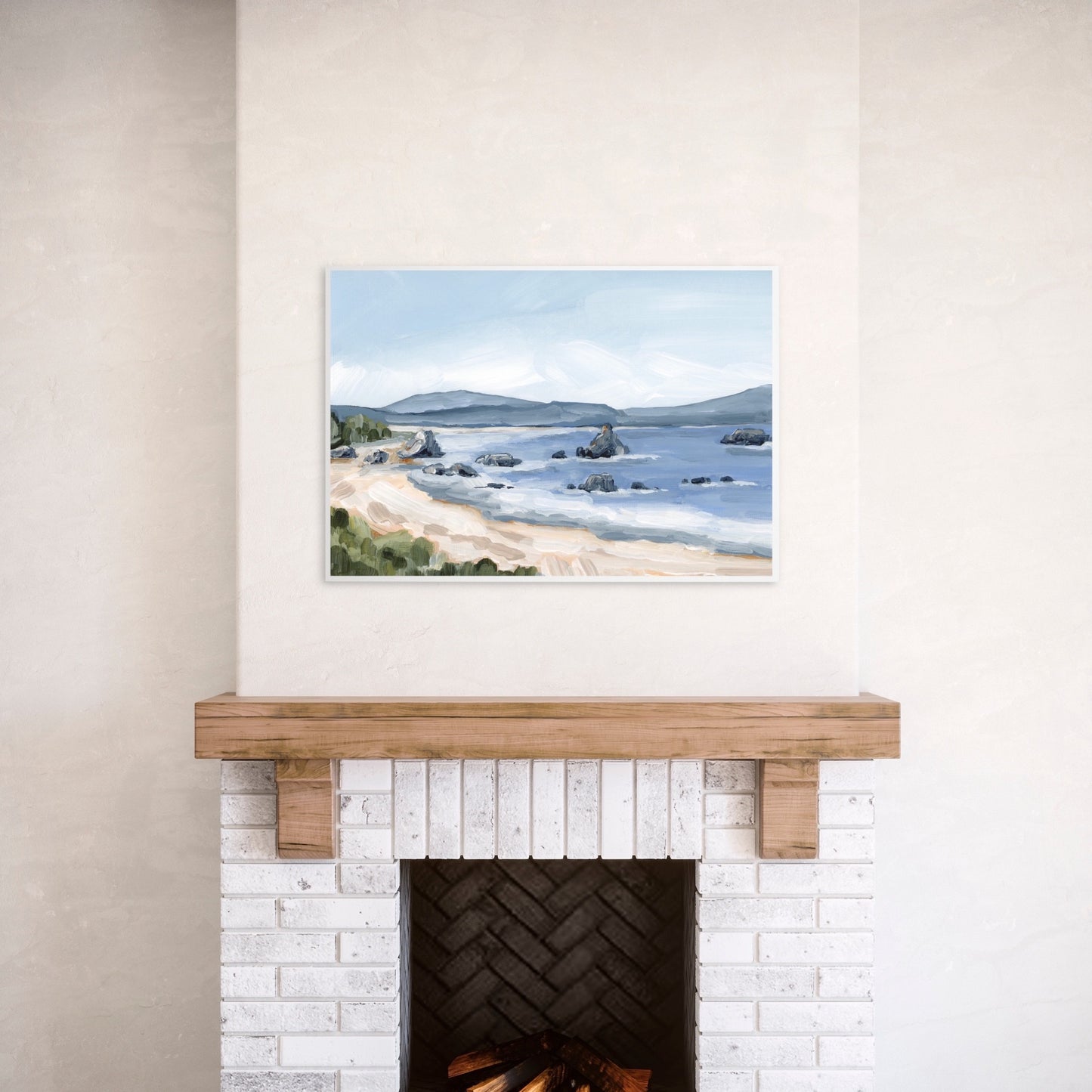 Framed coastal landscape painting hanging above a fireplace.