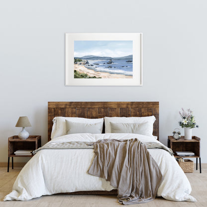 Bed with white bedding and wooden headboard beneath a framed coastal landscape painting.