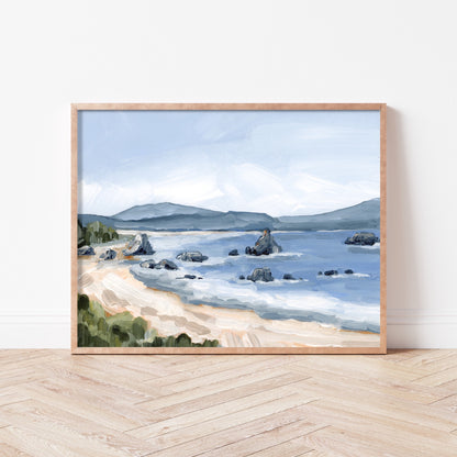 Framed painting of a coastal landscape with a beach, rocky outcrops, and distant mountains.