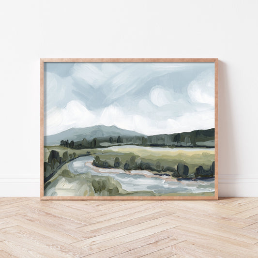 Framed landscape painting depicting a serene countryside with rolling hills and a winding river.