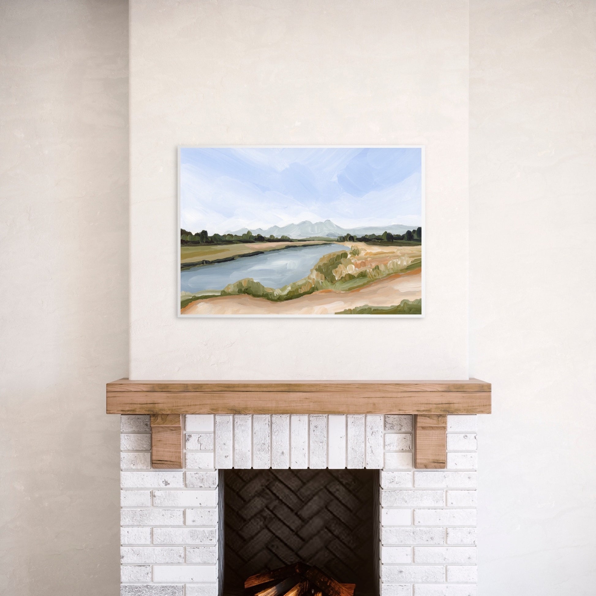 Landscape painting of a river winding through grassy fields displayed above a fireplace.